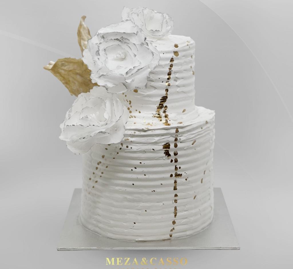 Pastel de boda blanco con flores y detalles dorados en dos pisos